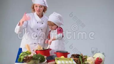 可爱的小男孩和他美丽的母亲在厨房<strong>做饭</strong>时微笑。 年轻的家庭在厨房<strong>做饭</strong>。 青年